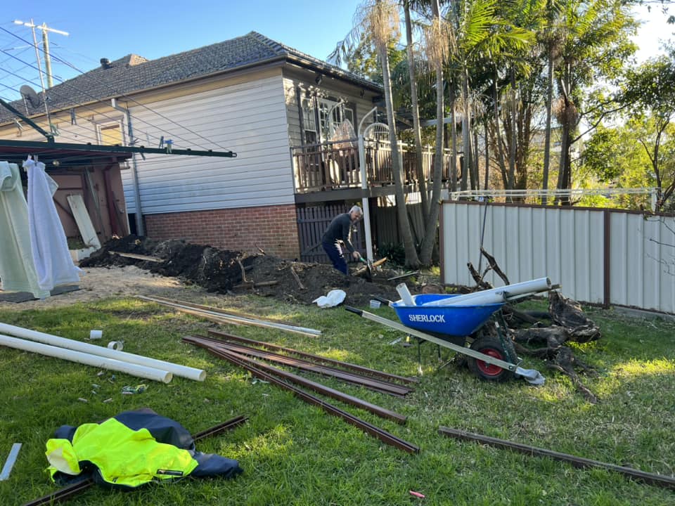 A backyard with various discarded construction materials, including pipes and scrap metal.