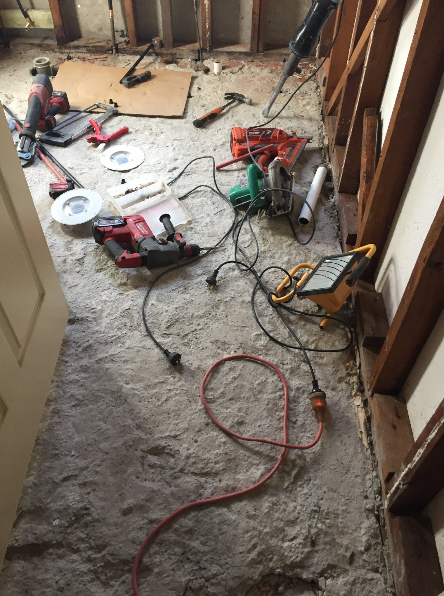  A construction site with exposed wooden framing, tools, and electrical wires spread across the unfinished floor.