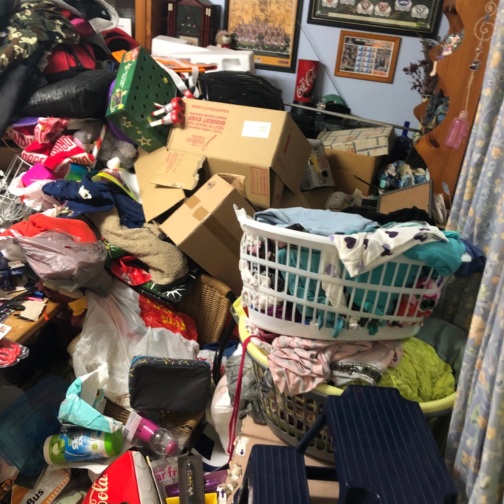 A cluttered storage space with shelves filled with kitchenware, tools, and miscellaneous items.