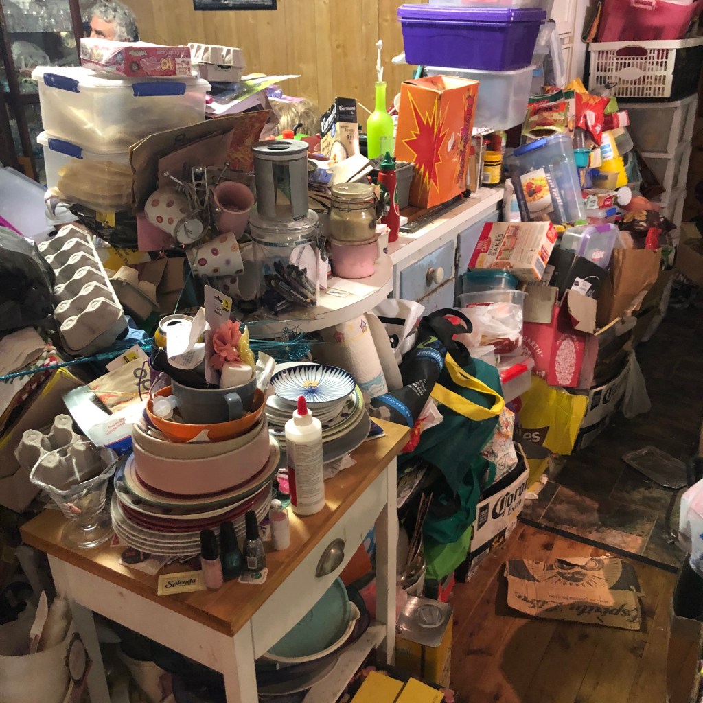 A cluttered storage space with shelves filled with kitchenware, tools, and miscellaneous items.