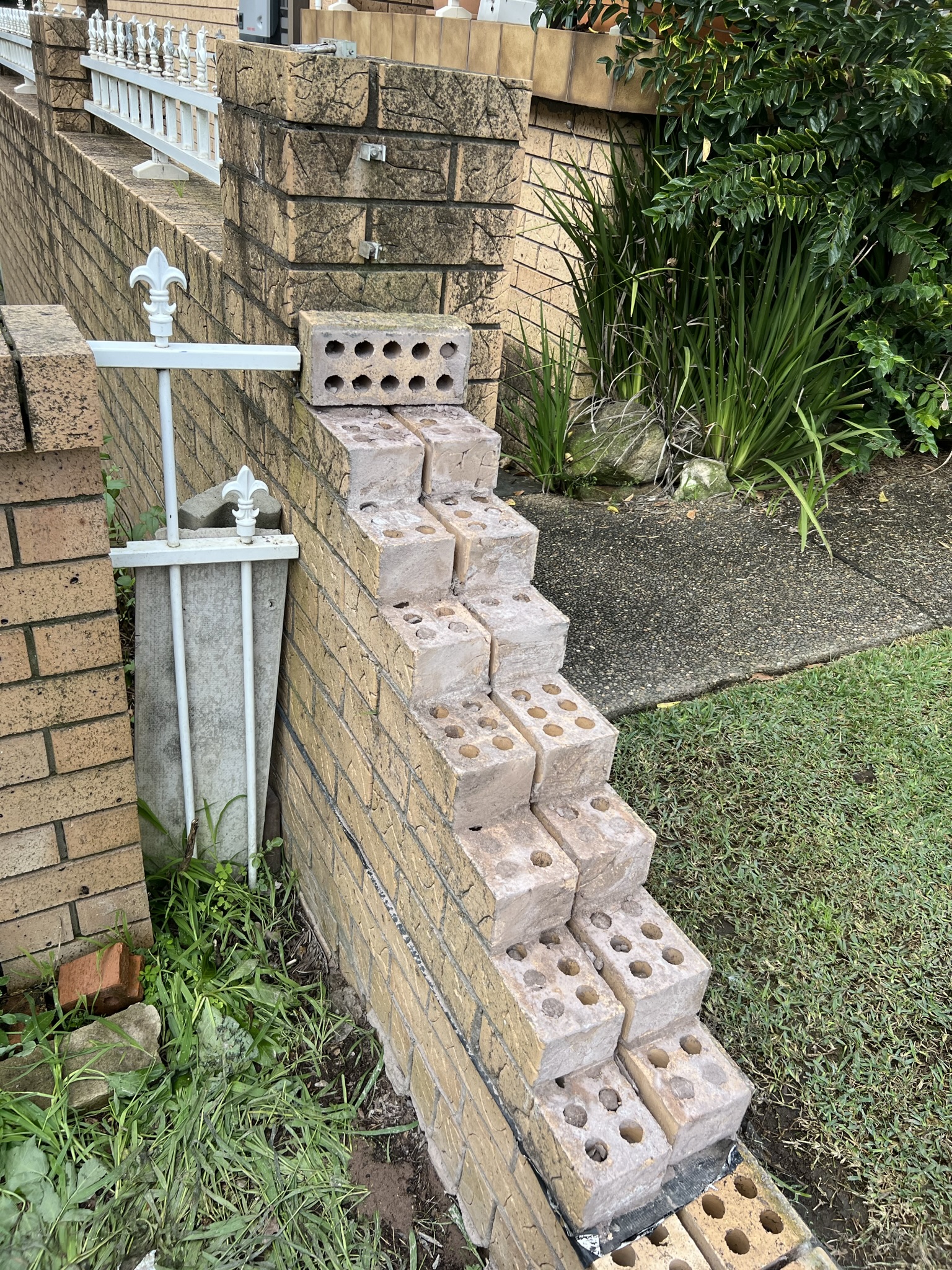 Laying fence brick work outside on a home boundary wall. Apart of our home improvement services.