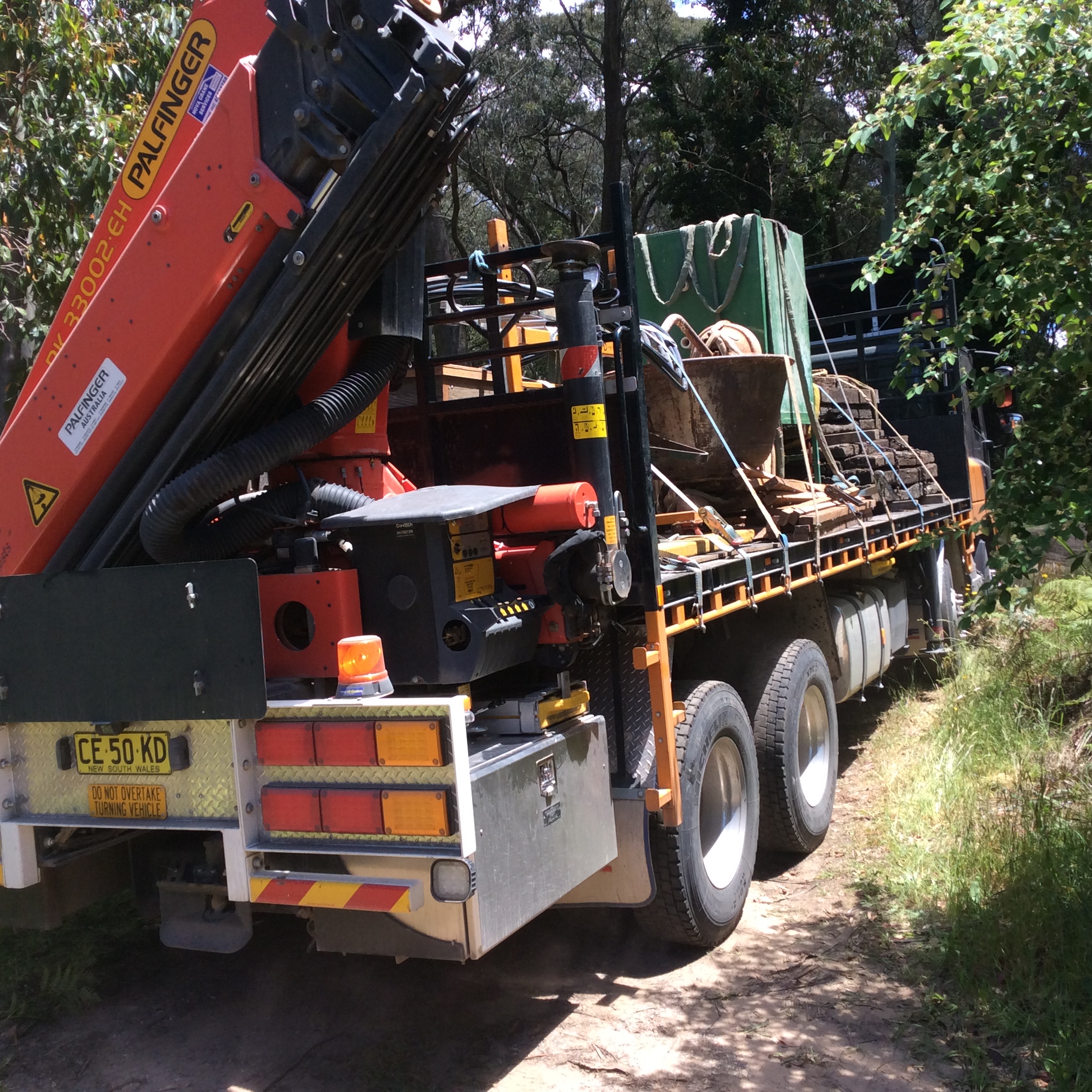 A crane-equipped truck lifting or transporting heavy materials at a work site.