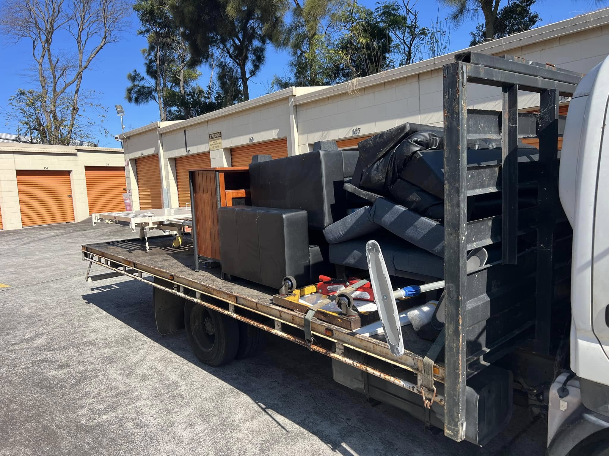 A loaded truck carrying discarded furniture, appliances, and household waste.