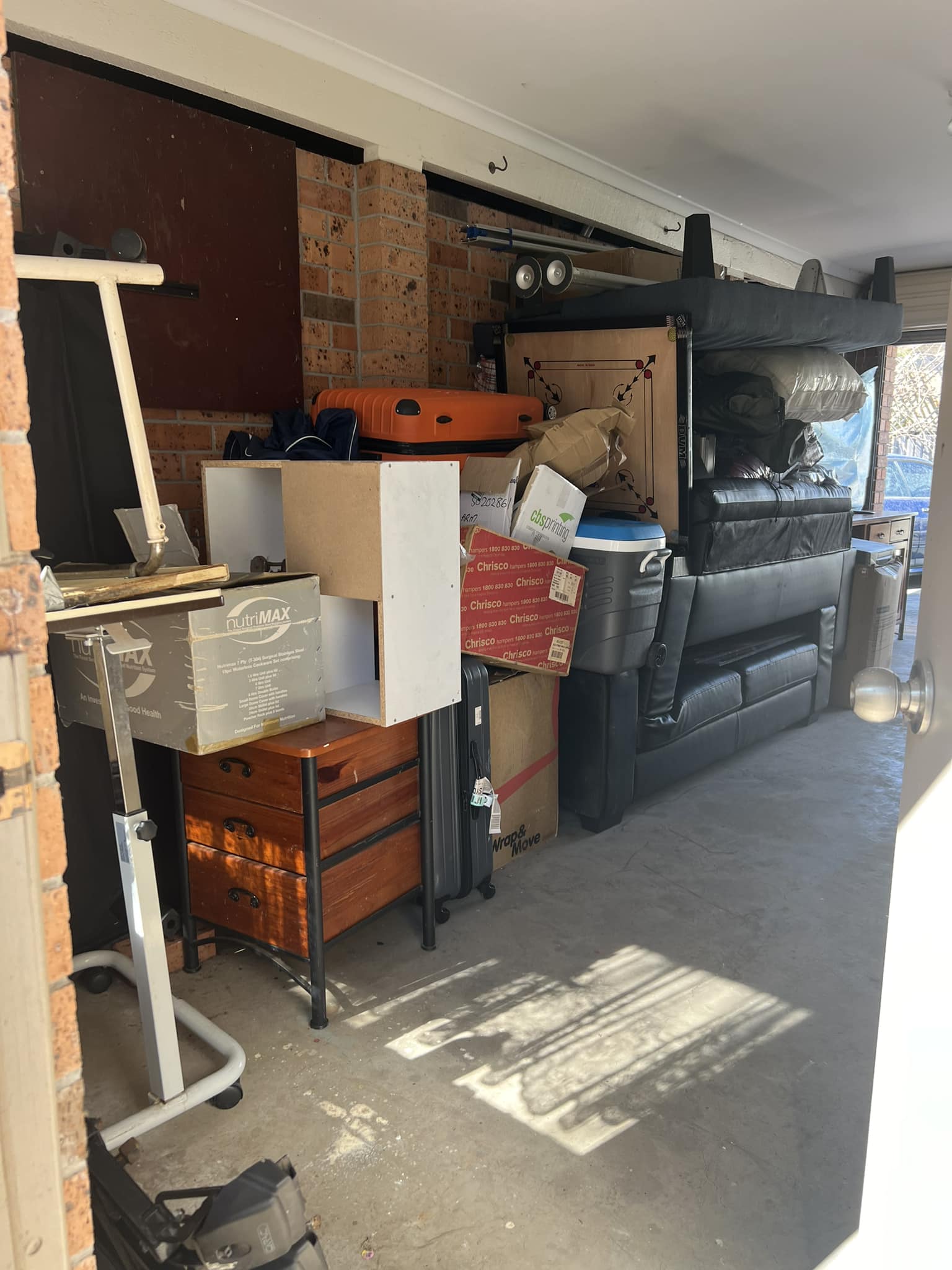 A garage or storage shed filled with old furniture, tools, and equipment.