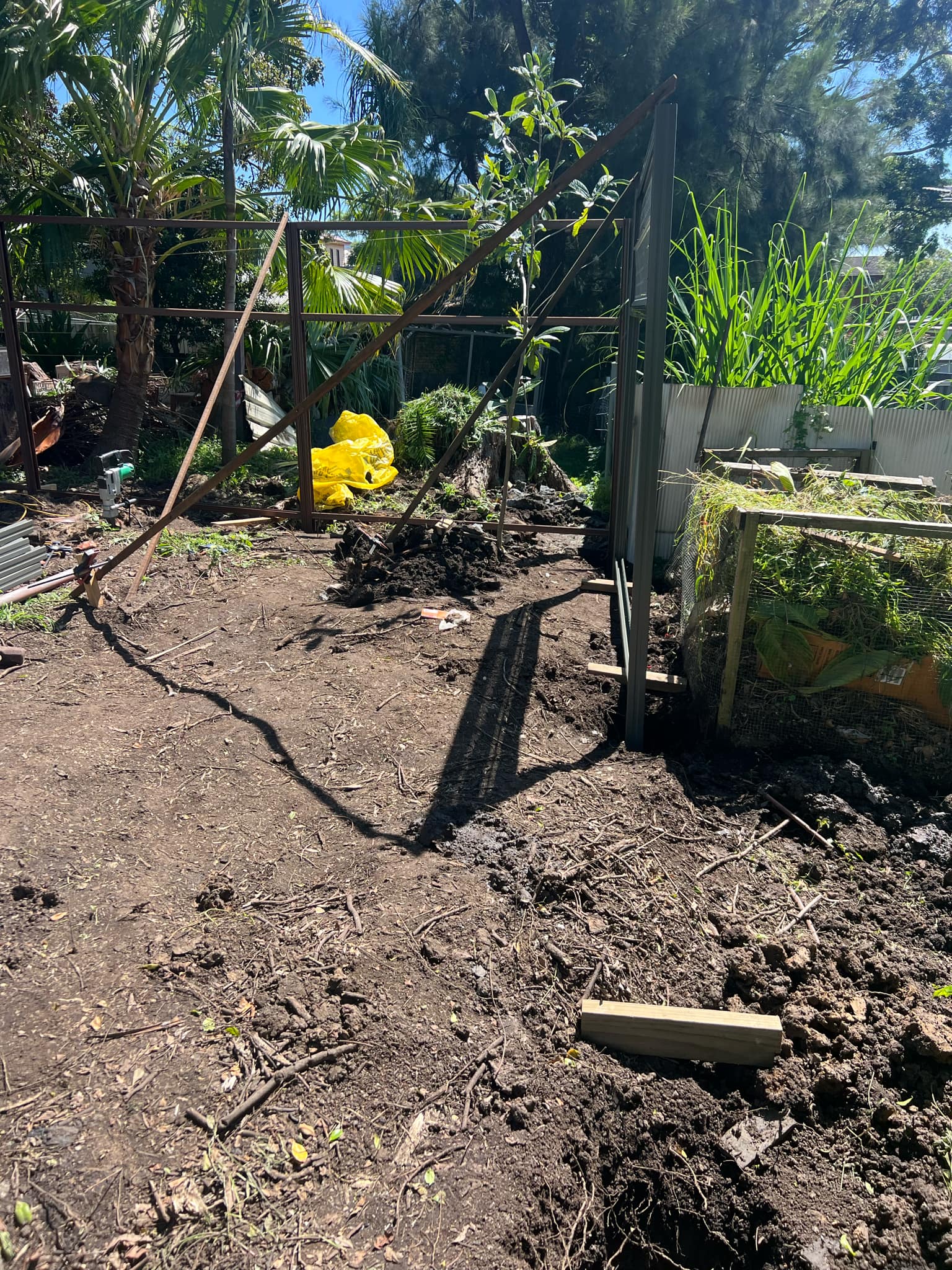 Dug-up soil with a shovel and some fencing materials nearby.
