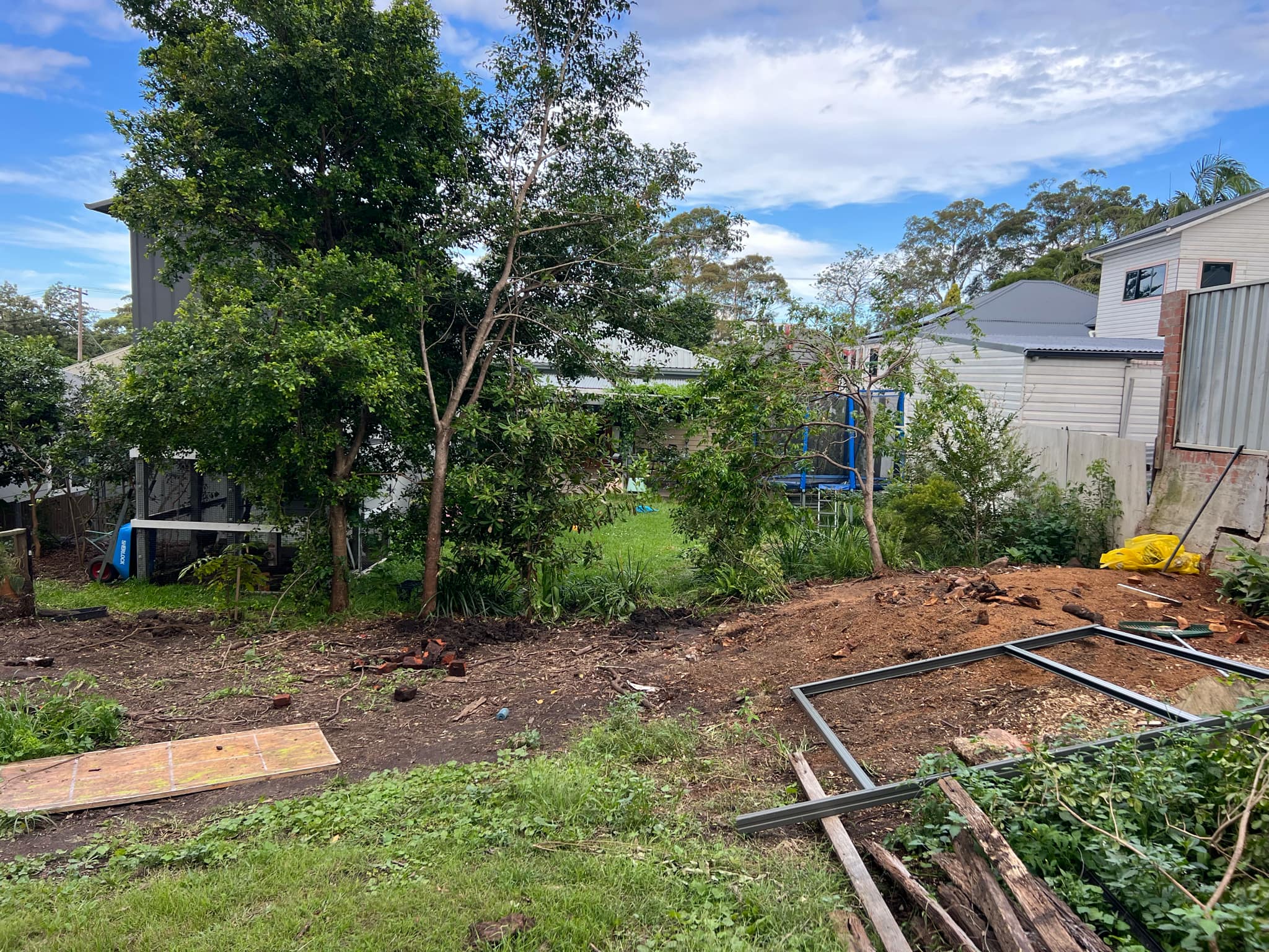 A piece of land with an upturned wheelbarrow and metal rods.