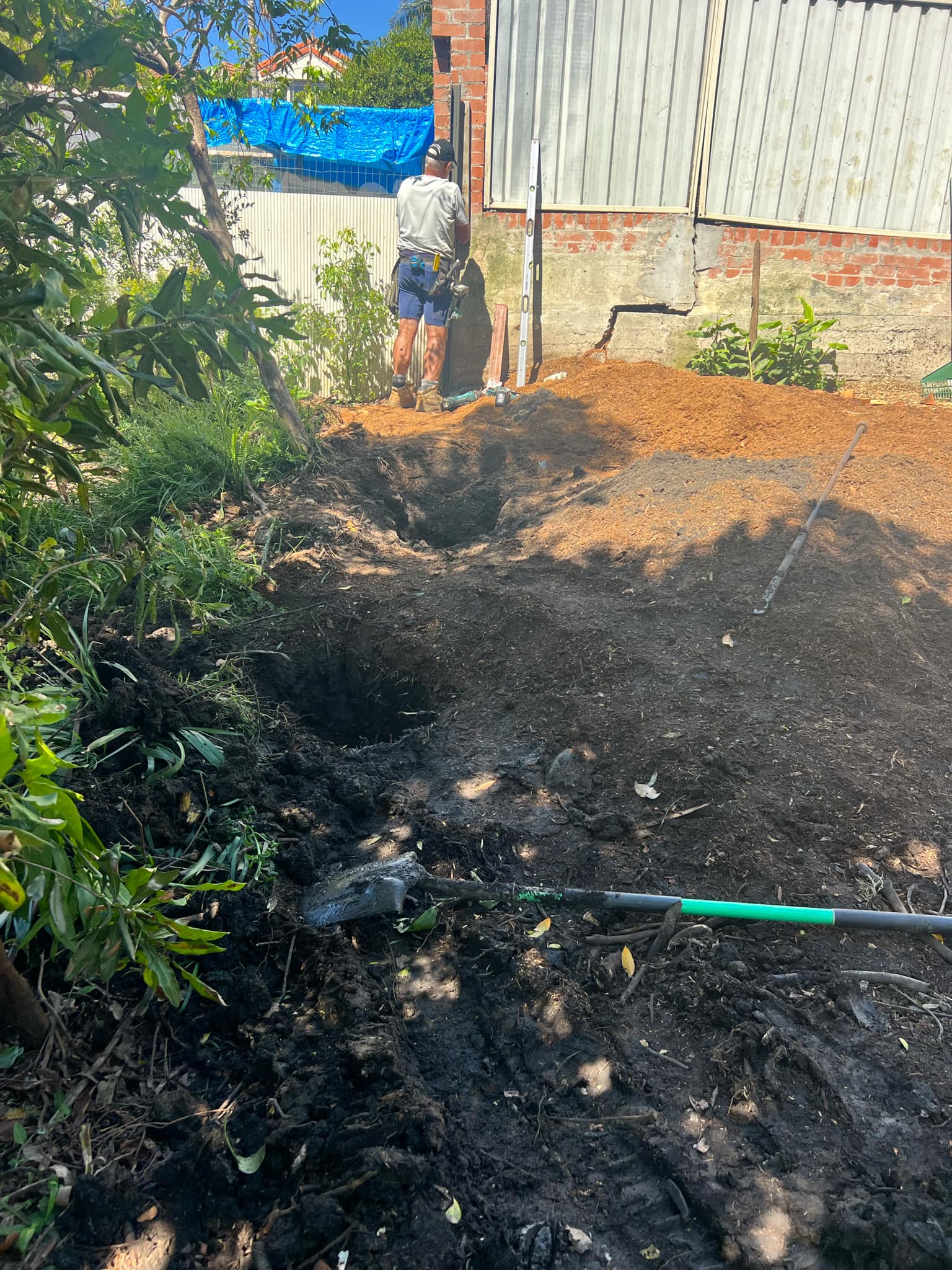 A person spreading soil over an area, preparing for landscaping.